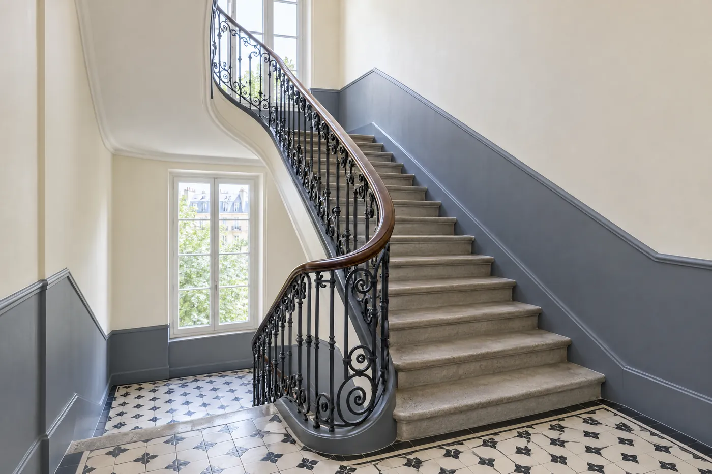 Cage d’escalier d’immeuble fraîchement repeinte avec rampe en fer forgé